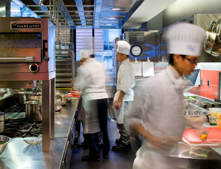 A detail shot of the kitchen of the George Brown Culinary School showing chefs at work.
