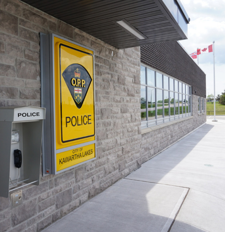 A closeup of the exterior of the Kawartha OPP with focus on the police phone and logo.