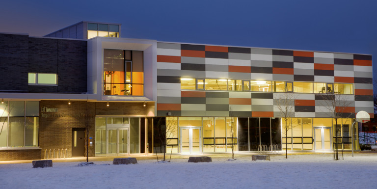 The exterior of the Regent Park Community Centre in winter at dusk.