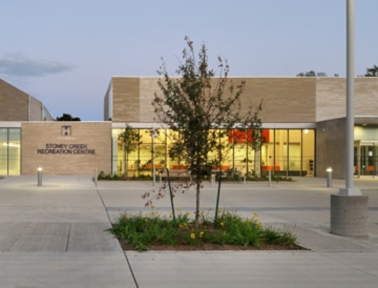 An exterior shot of the lighted Stoney Creek Community Centre at dusk.